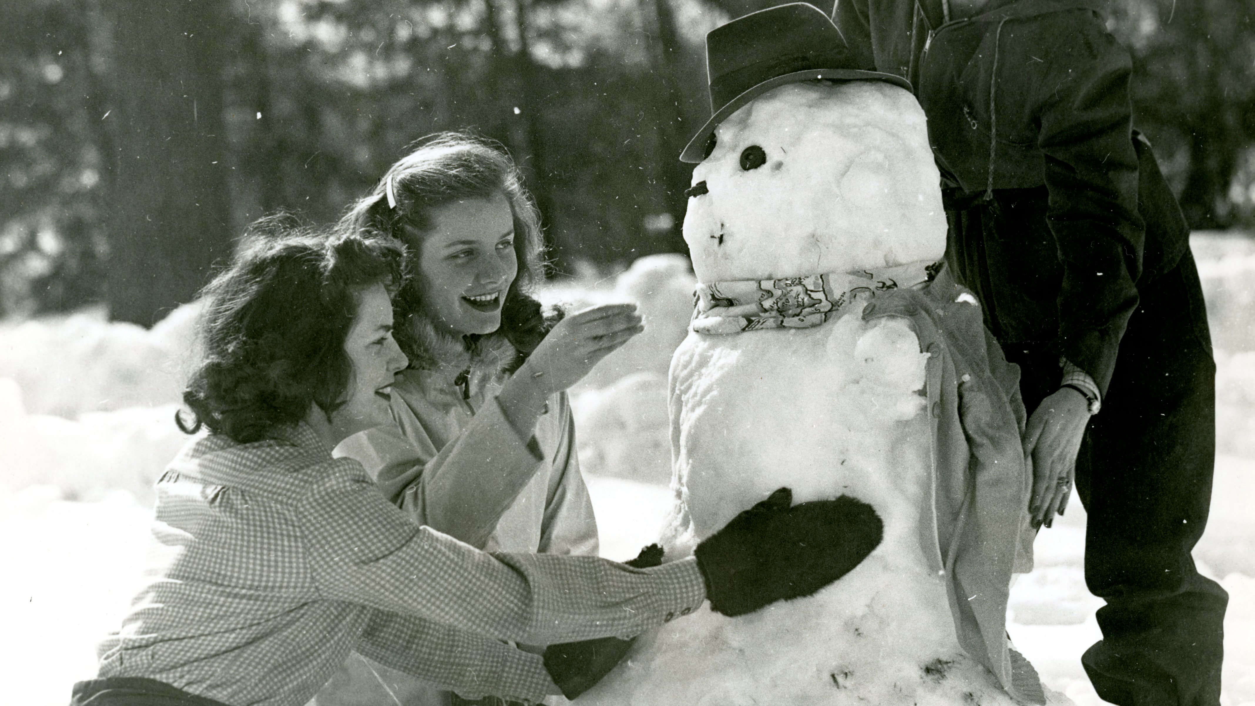 Two women joyfully making a snowman