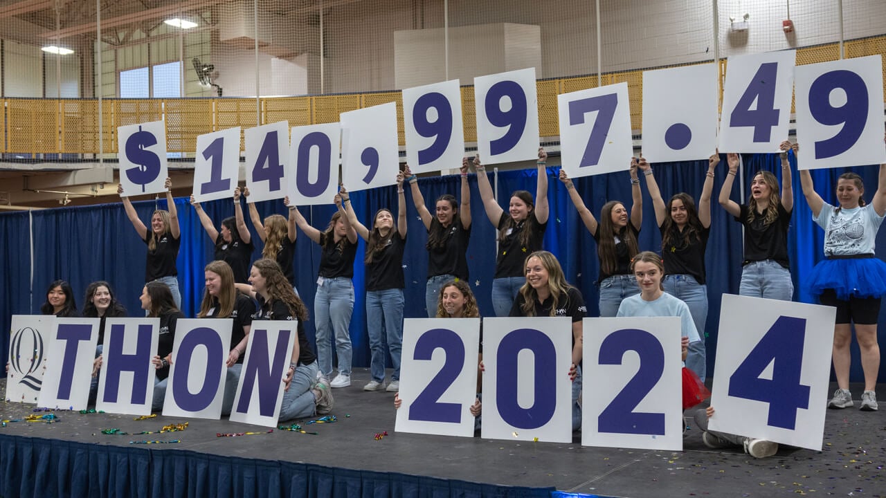 Students hold up cards with numbers to announce QTHON total