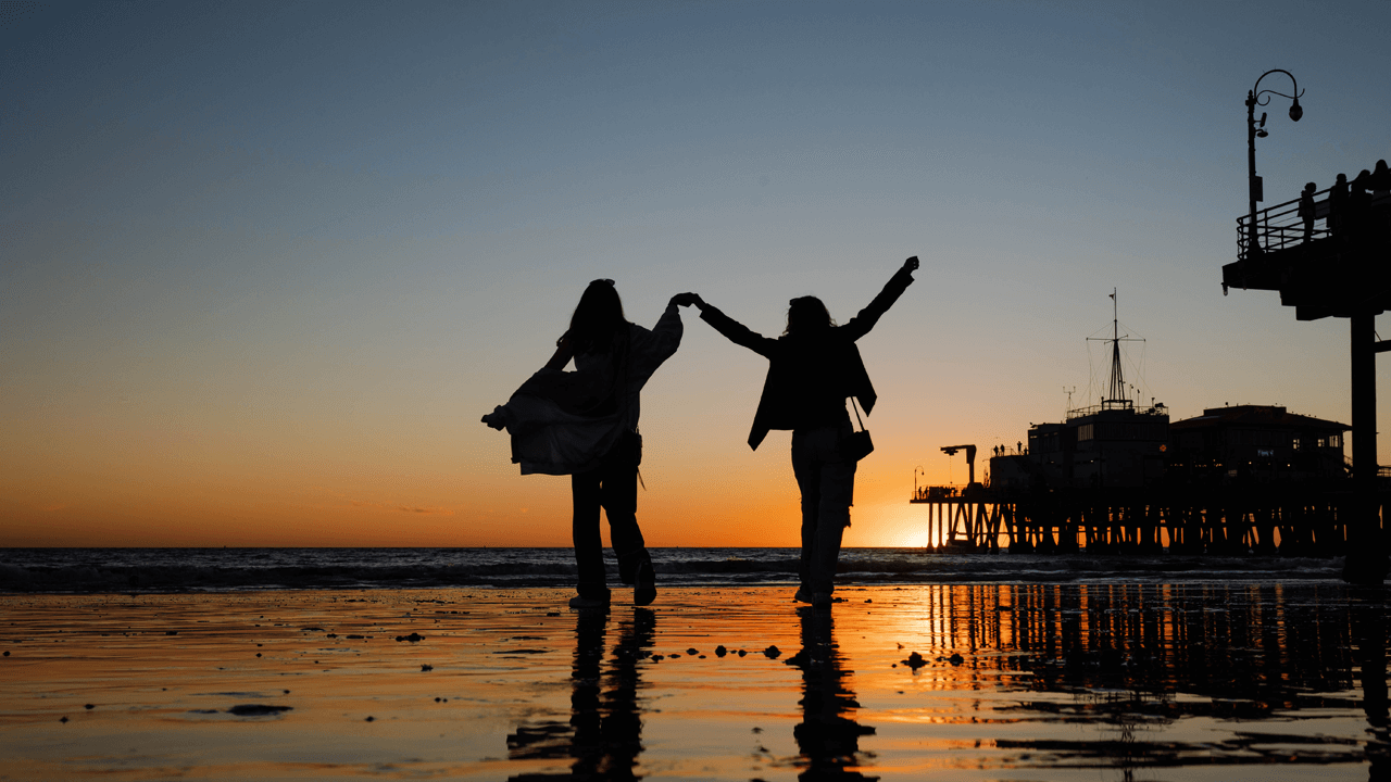 Two girls walking along beach in Santa Monica