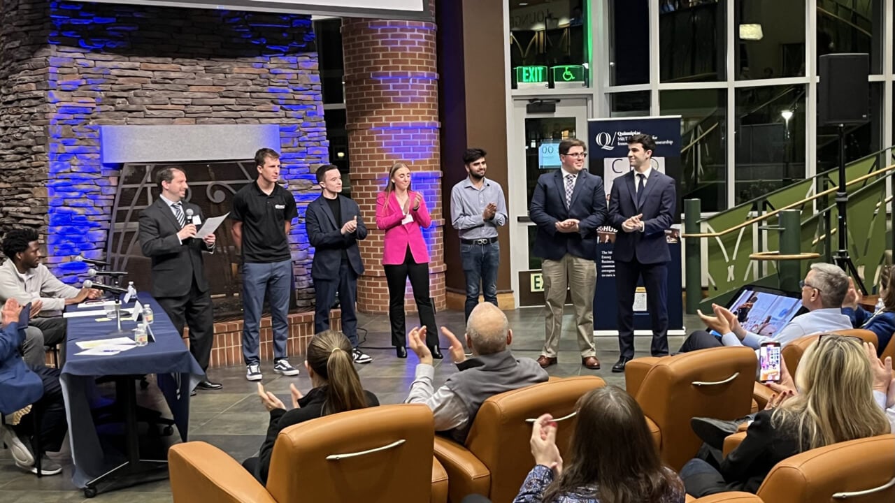 Students stand in front of judges at the pitch competition