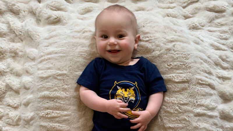 Baby Yatauro wears a QU Bobcats shirt and smiles broadly