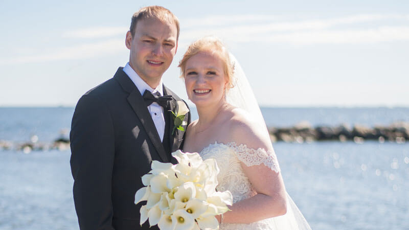 Gabrielle Stasiowski and Connor Jordan smile together on a beach on their wedding day