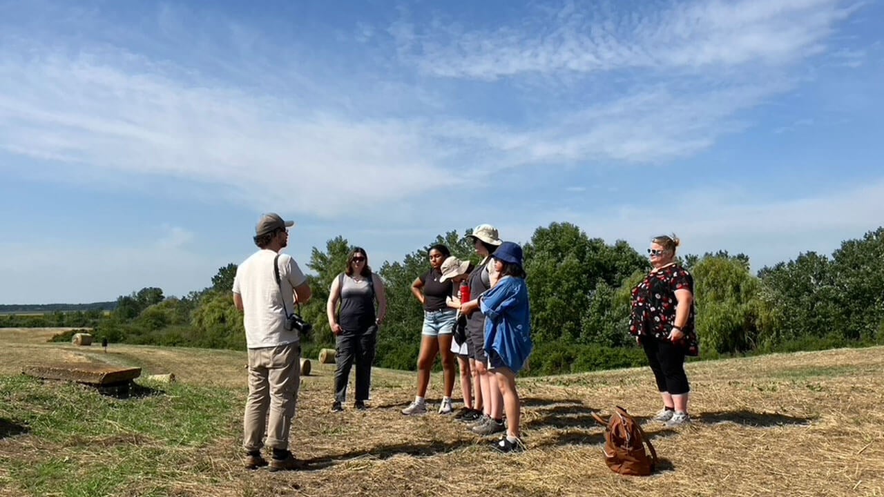 Students standing in a field listening to tour guide