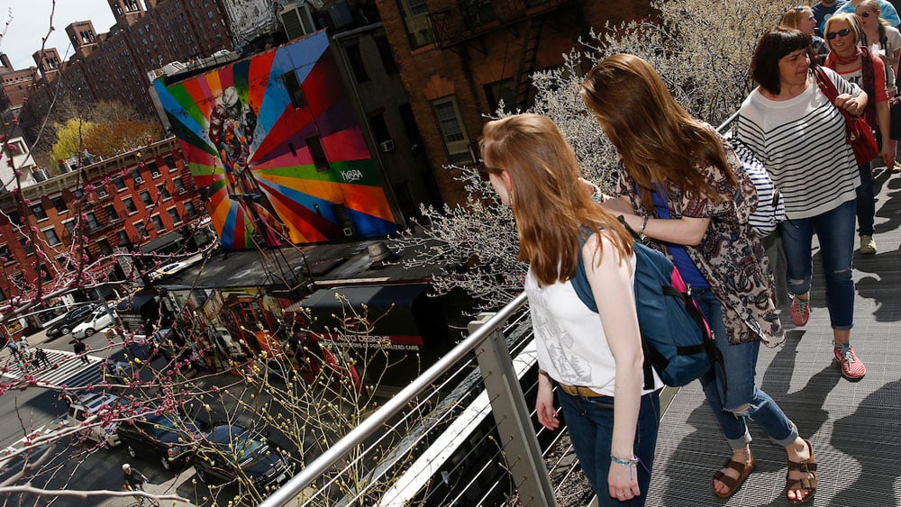 Two students look down from the High Line in New York City at the street below and a colorful mural.