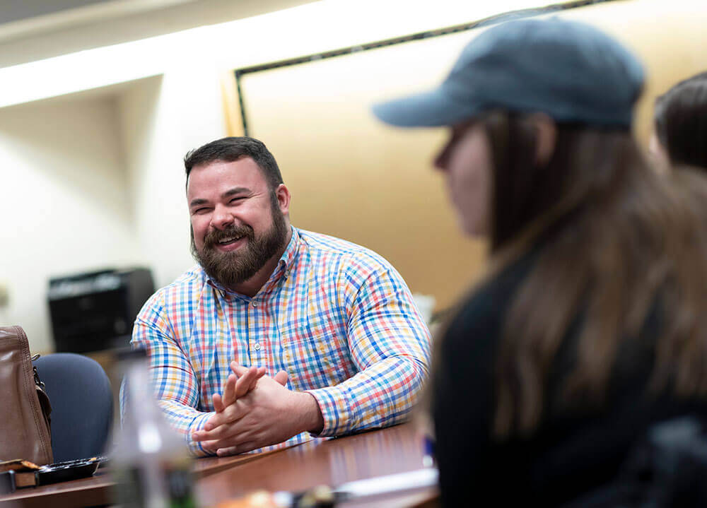 Psychology alumnus Adam Hoffman smiles while mentoring students during a lunch meeting