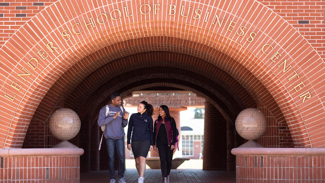 Students walk under the brick arch of the School of Business Center
