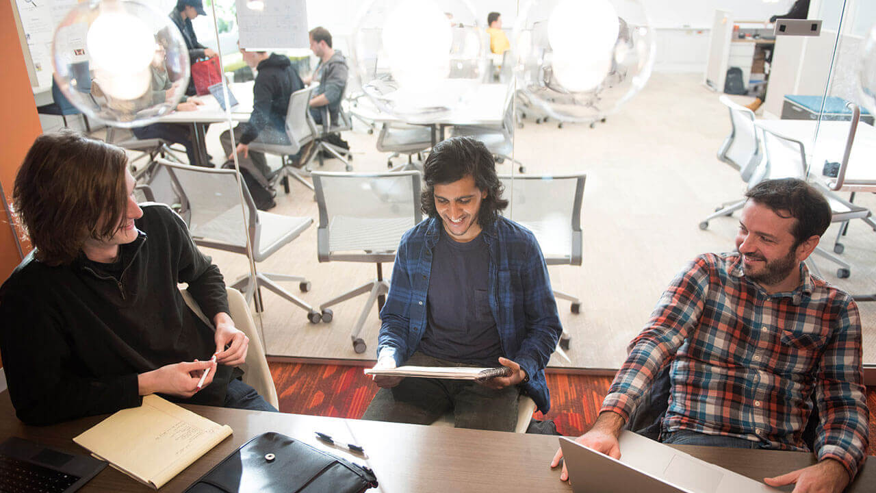Three students sit at a table in the Center for Innovation and Entrepreneurship