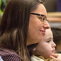 Sarah Obuchowski smiles and holds her daughter while attending a lecture