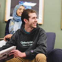 Student Michael Thorpe holding a textbook and smiling