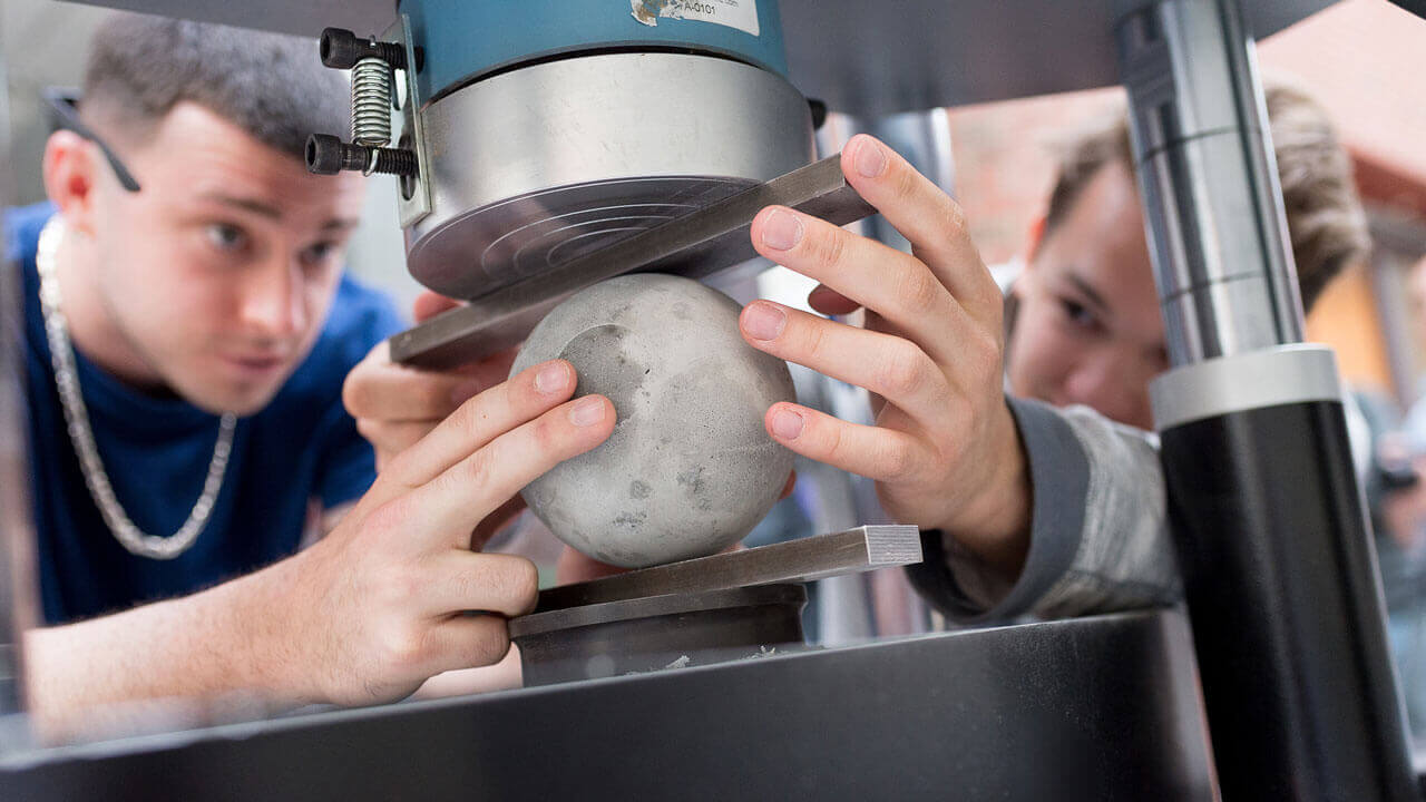 Students examine a bowling ball on a machine