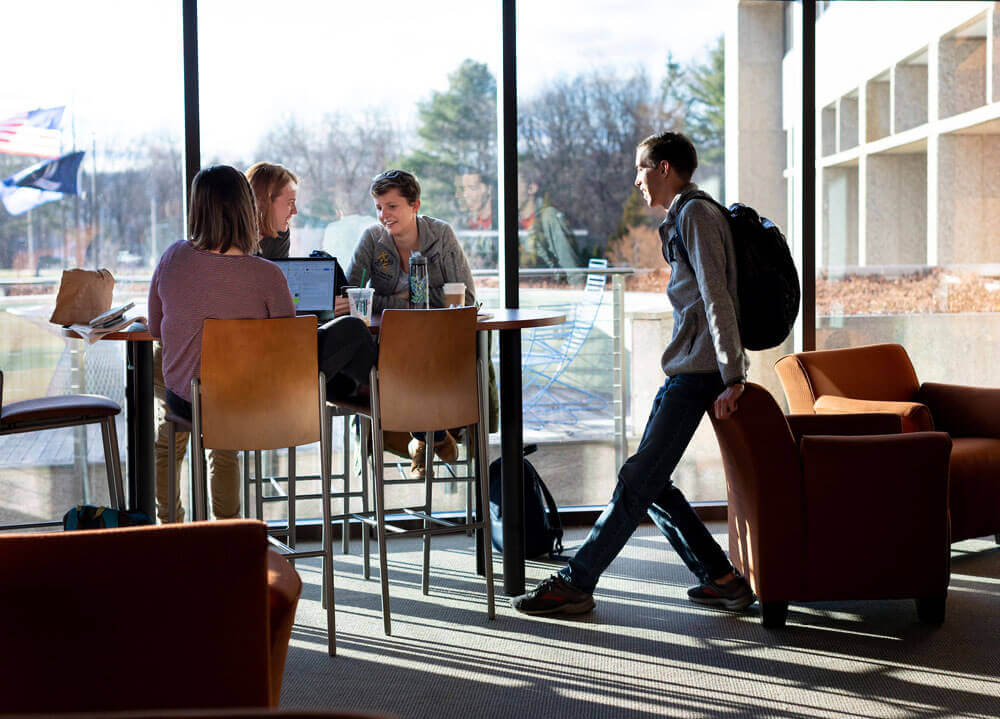 Students sit at a table together in the student lounge