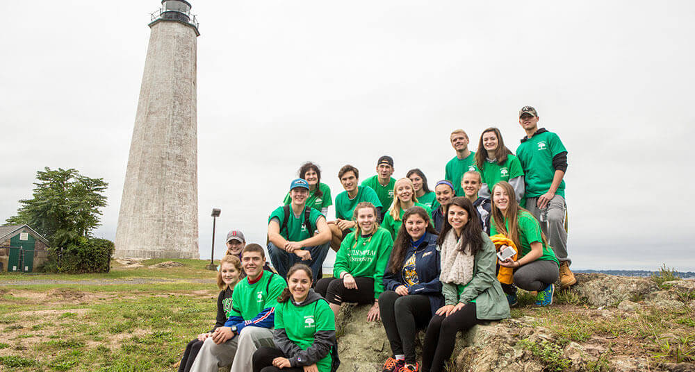 A group of PT students pose in front of a lighthouse in New Haven