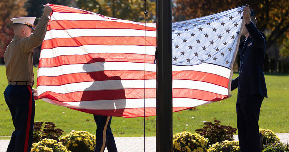 Three student veterans participate in a flag raising ceremony
