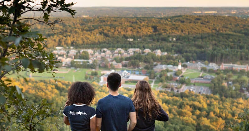Three students look out on the Mount Carmel Campus from the Sleeping Giant peak