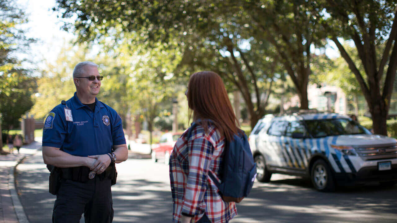 Public safety officer in uniform speaks with a student who is wearing a backpack.