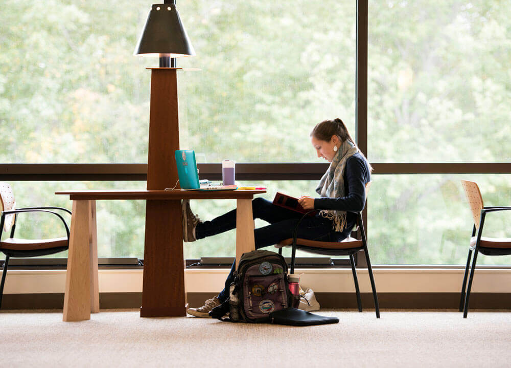 A student studies in front of big windows on the North Haven Campus
