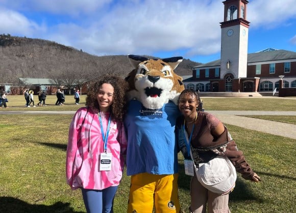 Two students smiling joyfully with Boomer the Bobcat