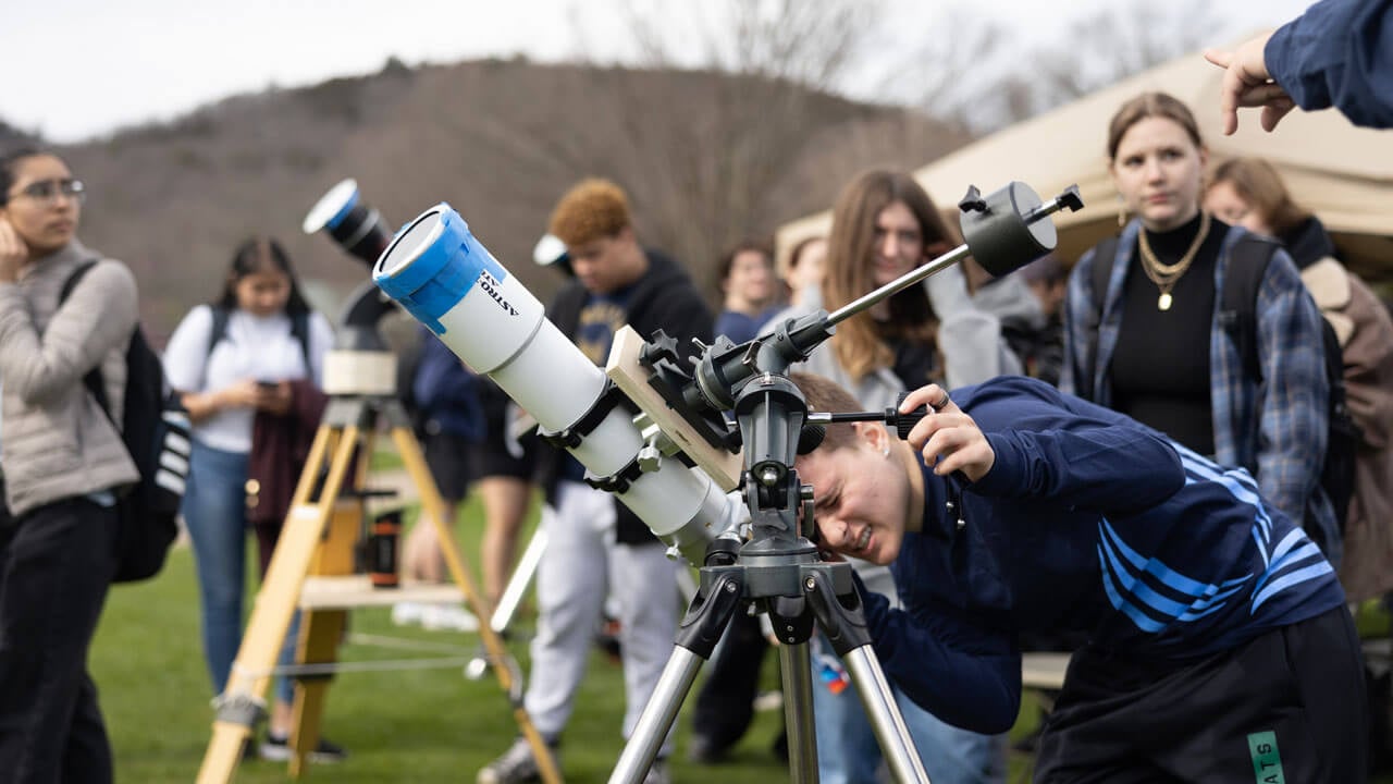 A student looks through a telescope.