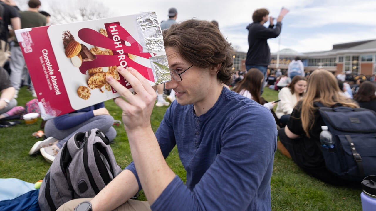 A student looks through a cereal box during the solar eclipse.
