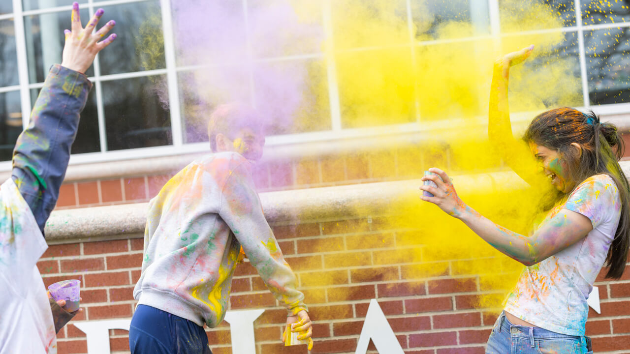 Students celebrating Holi, the Festival of Color with the tradition of throwing colored powder at one another.