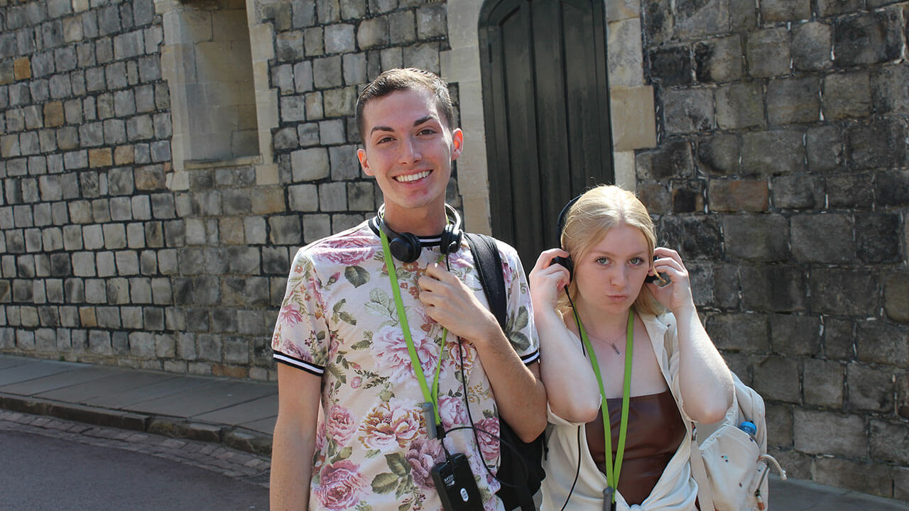 two students pose with their audio headsets for their tour