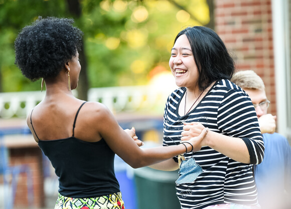Two students greet each other at a cultural global dinner on the Mount Carmel campus.