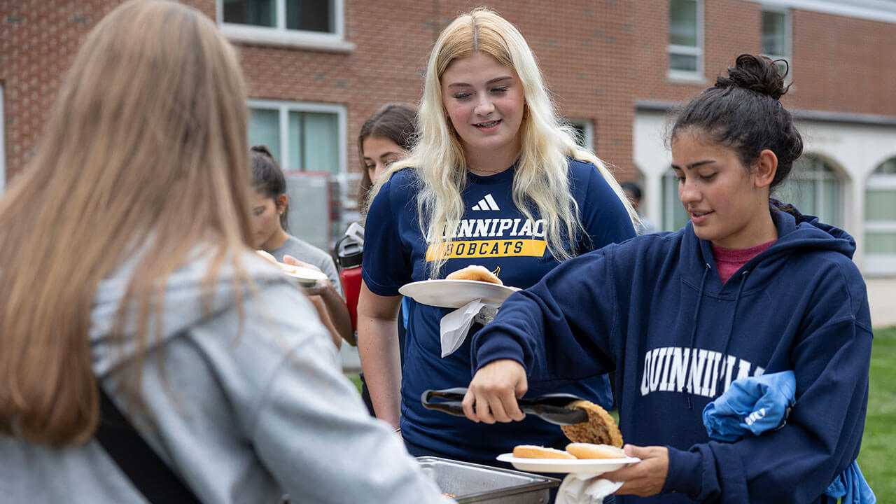 Girls in Quinnipiac spirit wear getting food from buffet