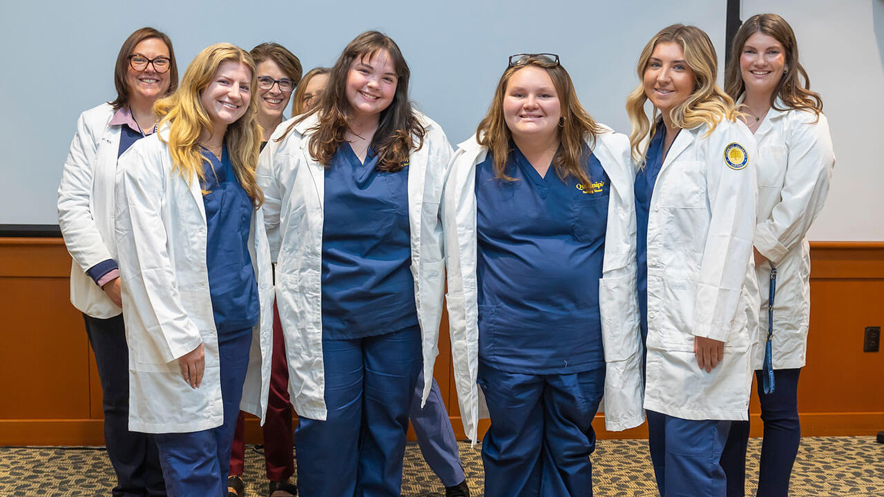 four nursing students show off their new white coats