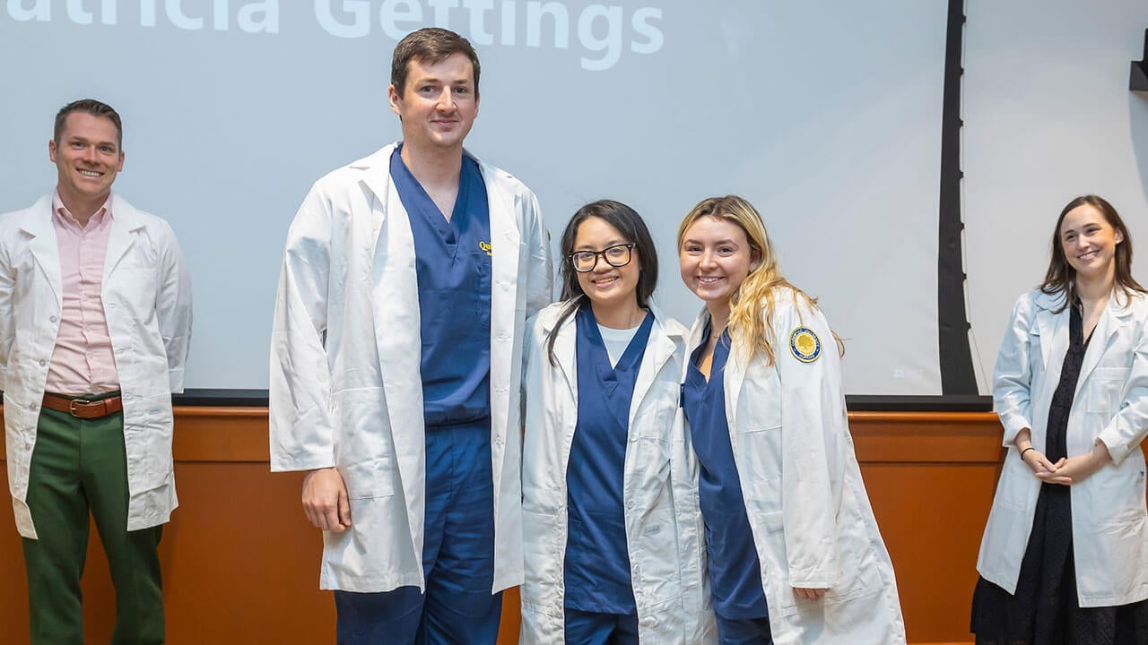 three nursing students pose together wearing their new white coats