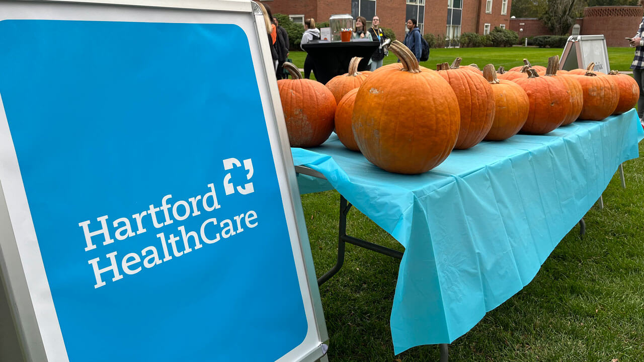 A Hartford Healthcare sign next to a table with dozens of pumpkins on it