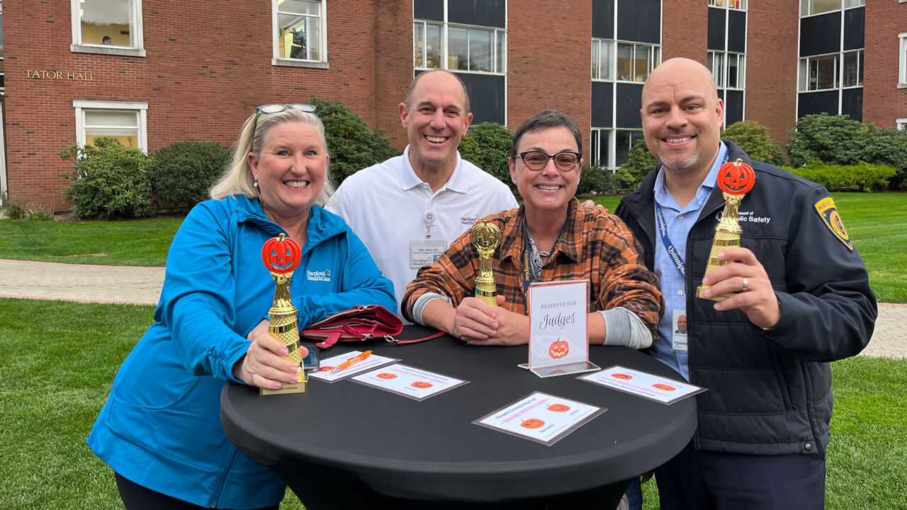 Four people pose with trophies at the judges' table at pumpkin carving