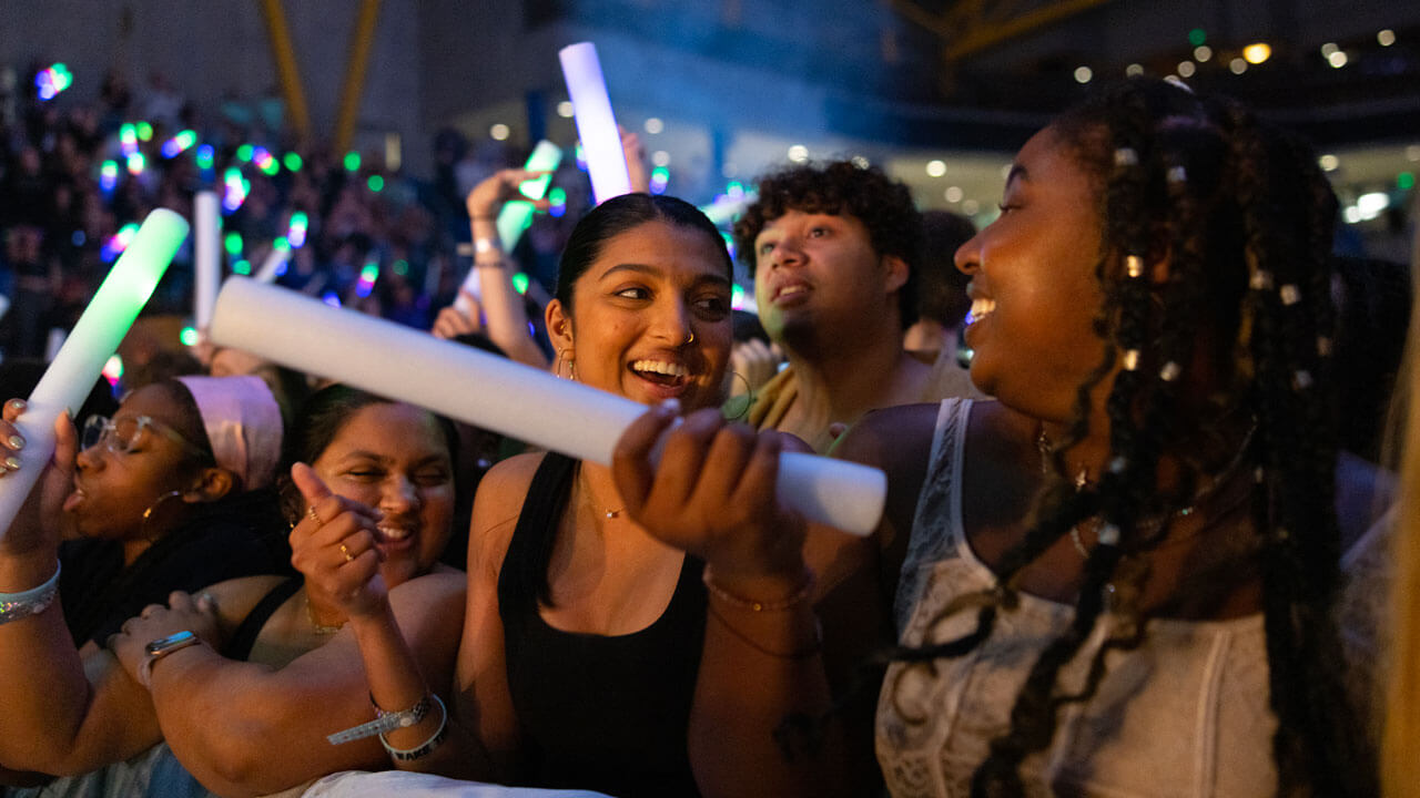 Students smile and wave around glowsticks at the Wake the Giant concert.