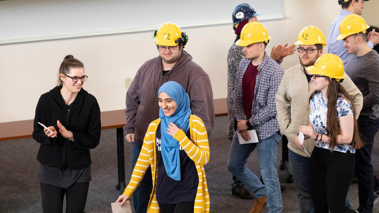 A group of students wearing Quinnipiac-branded hard hats