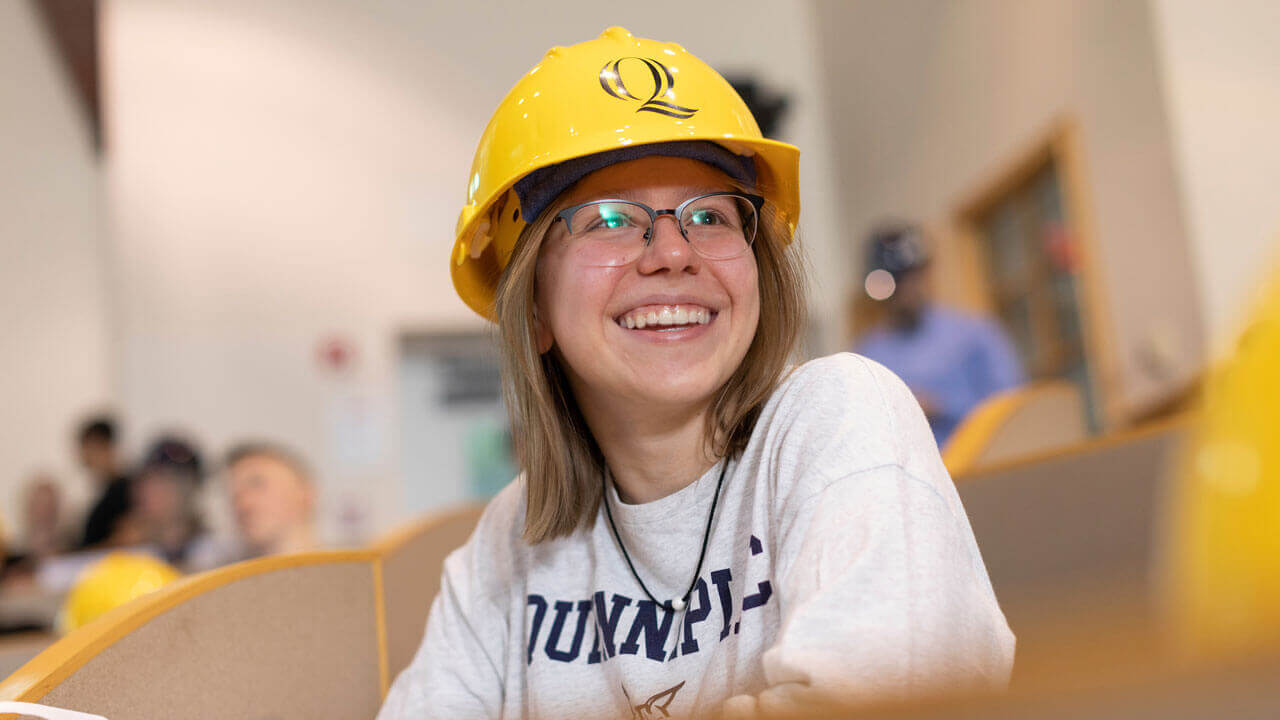 Student smiling while wearing Quinnipiac-branded hard hat